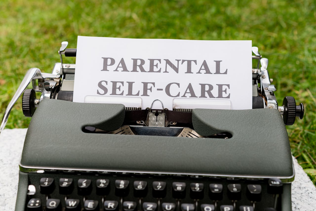 A vintage typewriter showcasing a Parental Self-Care message on paper outdoors.