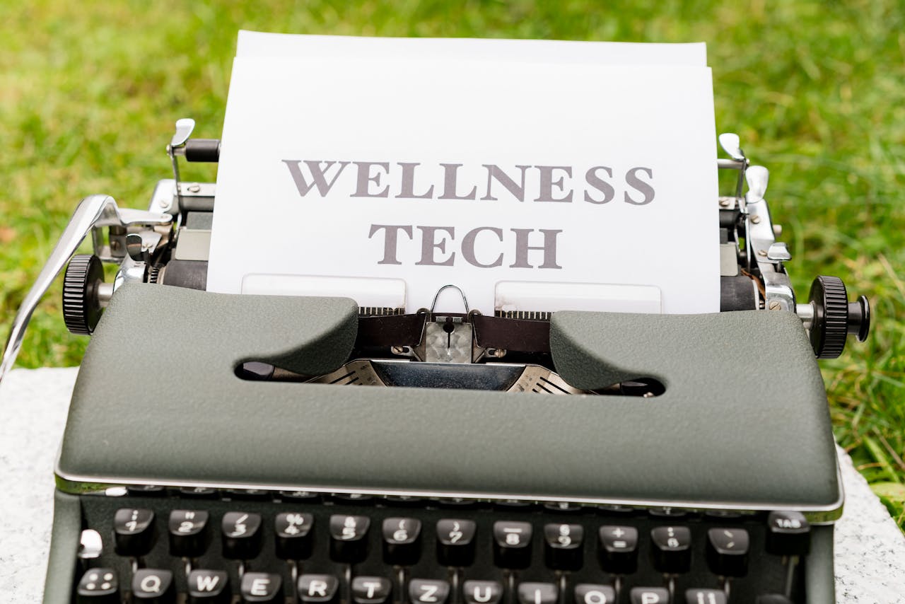 A retro typewriter outdoors displaying a Wellness Tech message on paper.
